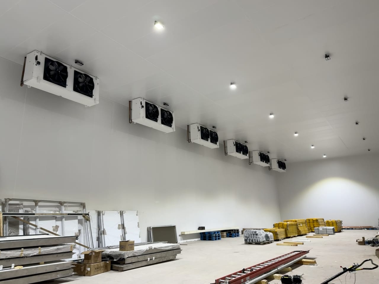 Ambiente frigorificado amplo com equipamentos instalados próximos ao teto.