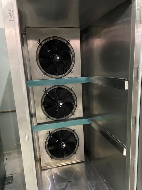 Equipamento metálico aberto com três ventiladores internos.
